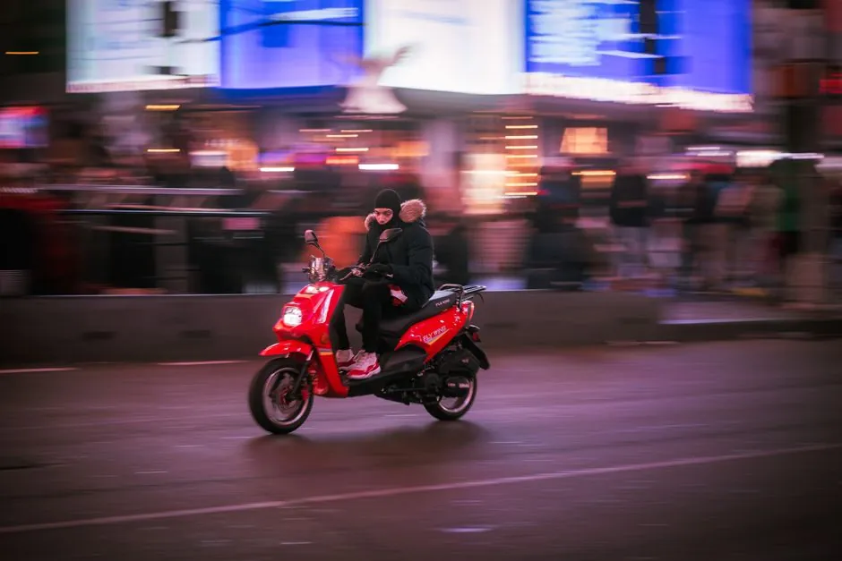 Pilote posant un casque sur une moto de grosse cylindrée à côté d'un scooter 125 dans un garage